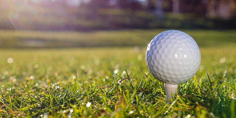 golf ball on tee in grass