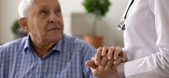 elderly male patient holding doctor's hands