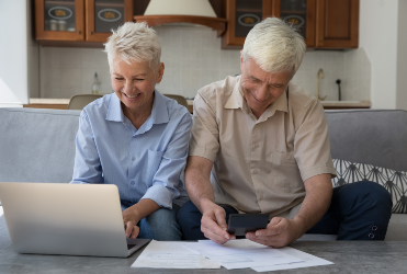 older couple on sofa paying bills
